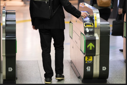 A person using an IC card to enter or exit a train station, tapping the card on a contactless reader at the gate.