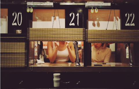 A woman in a Japanese restaurant paying for her meal without leaving a tip, as tipping is not customary in Japan.