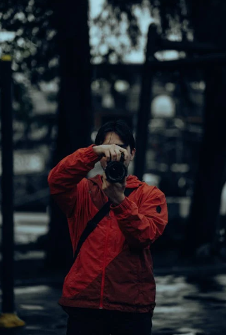 "A man taking a photograph with a camera focused on capturing an image, with his attention directed at the subject of the photo