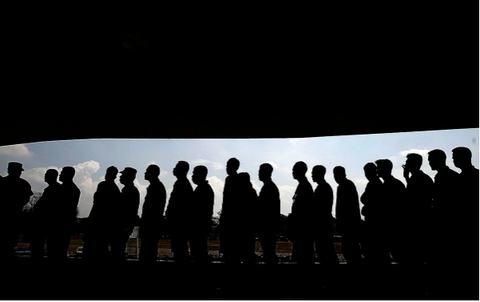 "People in Japan standing in a neat, orderly line, waiting their turn at a service counter, train platform, or other public area, following the practice of queueing politely.